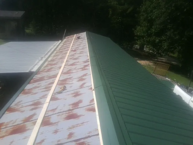 Old rusted panels beside newly installed green metal roofing — Wind Damage Roof Repair by Roofing Brothers in Akron