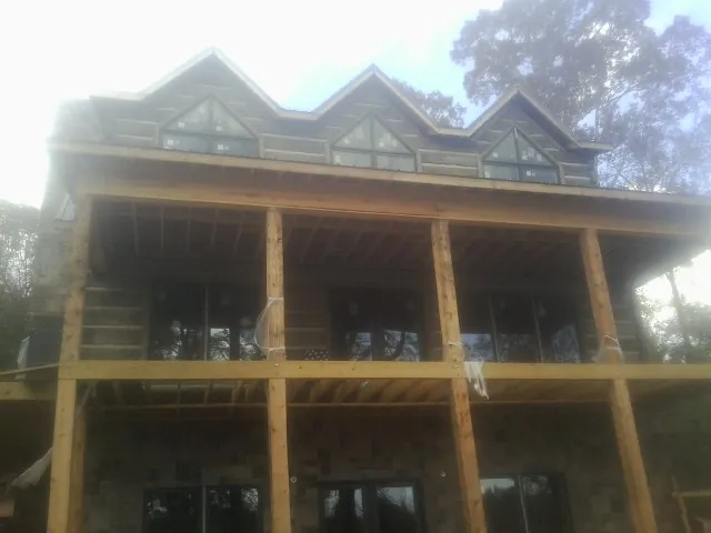 Dormers and porch framing on a large log home under construction — Roof Coating work by our crew in Akron